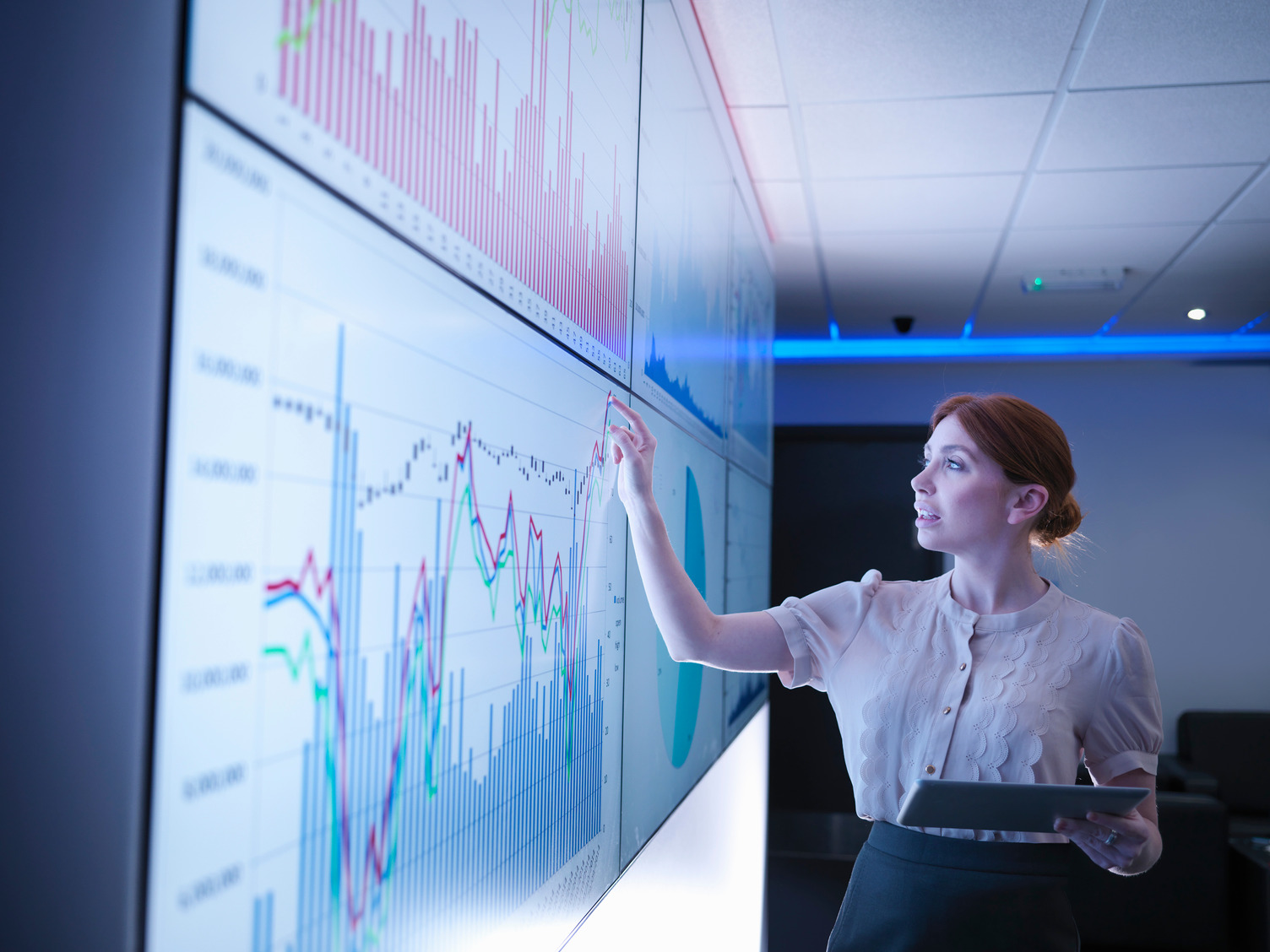Businesswoman studying graphs on screens